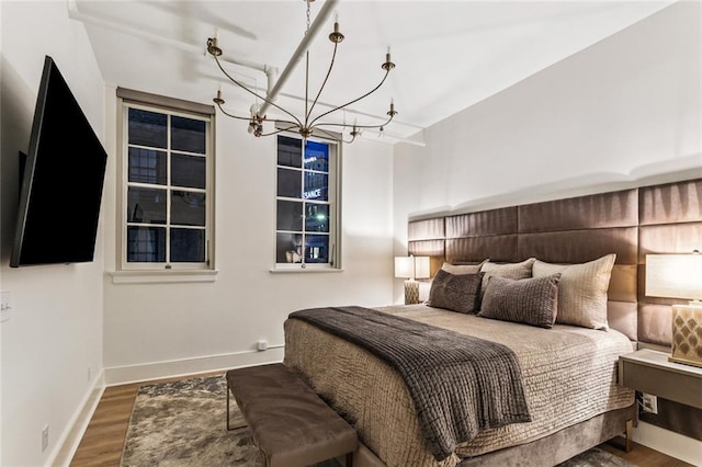 bedroom featuring wood finished floors, a chandelier, and baseboards
