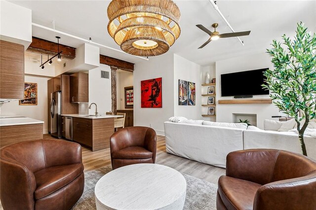 living room featuring light wood finished floors, a ceiling fan, visible vents, and baseboards