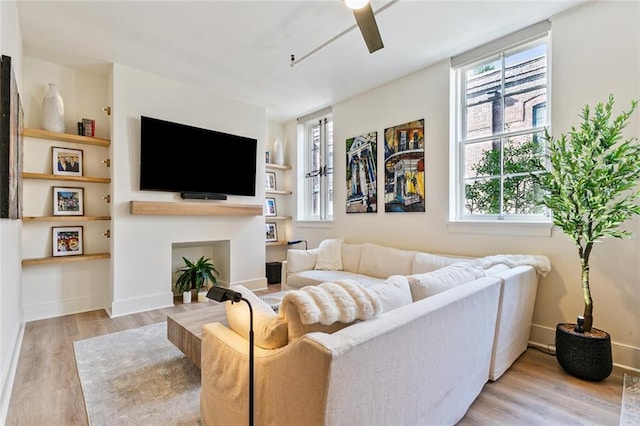 living area with a ceiling fan, wood finished floors, and baseboards