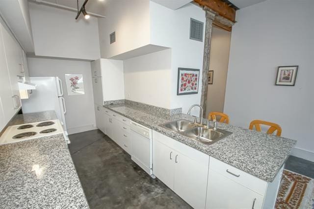 kitchen featuring white appliances, a sink, visible vents, concrete flooring, and a peninsula
