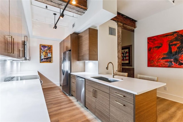 kitchen with a sink, visible vents, stainless steel appliances, light wood finished floors, and track lighting
