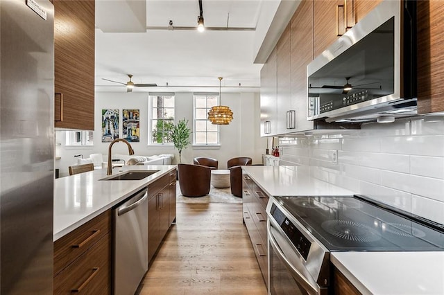 kitchen with ceiling fan, appliances with stainless steel finishes, light countertops, and a sink