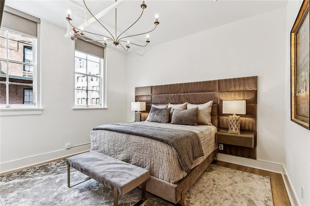 bedroom with a notable chandelier, wood finished floors, and baseboards