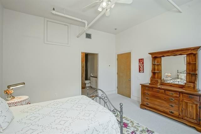 bedroom with light colored carpet, ensuite bathroom, visible vents, a ceiling fan, and a towering ceiling