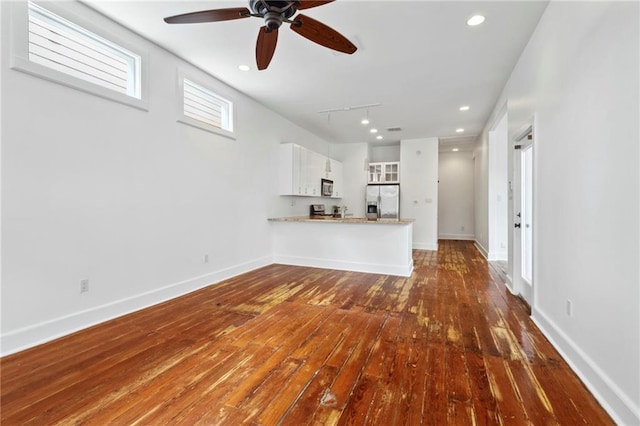 unfurnished living room with rail lighting, ceiling fan, hardwood / wood-style floors, and baseboards