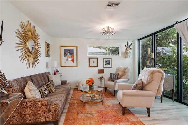living room with visible vents, expansive windows, and light wood-type flooring