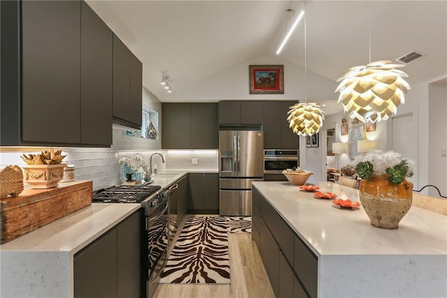 kitchen featuring backsplash, vaulted ceiling, a kitchen island, pendant lighting, and appliances with stainless steel finishes