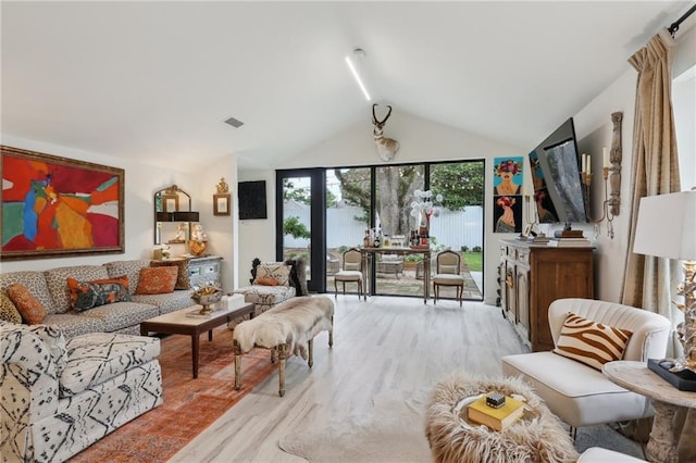 living area with visible vents, vaulted ceiling, and light wood-style floors