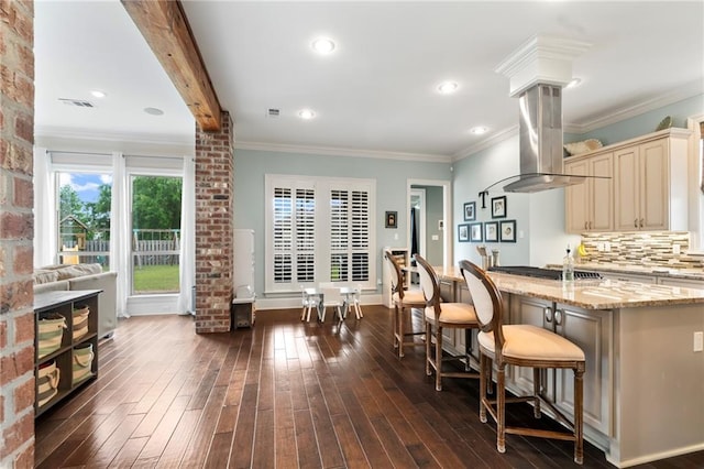274 W Longview Ct, Madisonville, LA 70447 - kitchen featuring decorative columns, light stone counters, dark wood finished floors, island range hood, and cream cabinetry