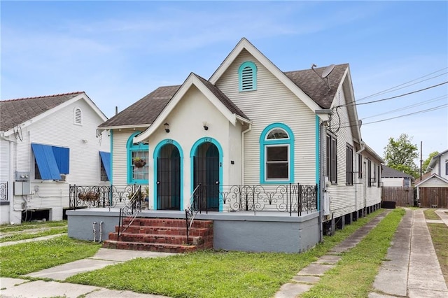 view of front facade with covered porch, fence, a front lawn, and roof with shingles