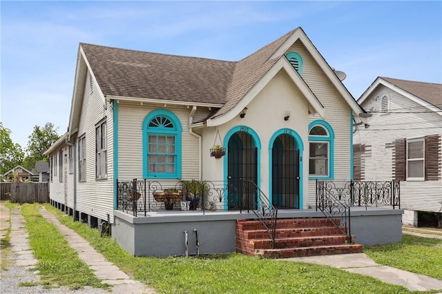 view of front facade featuring roof with shingles and covered porch