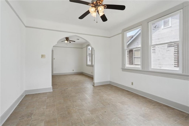 empty room with a ceiling fan, baseboards, and arched walkways
