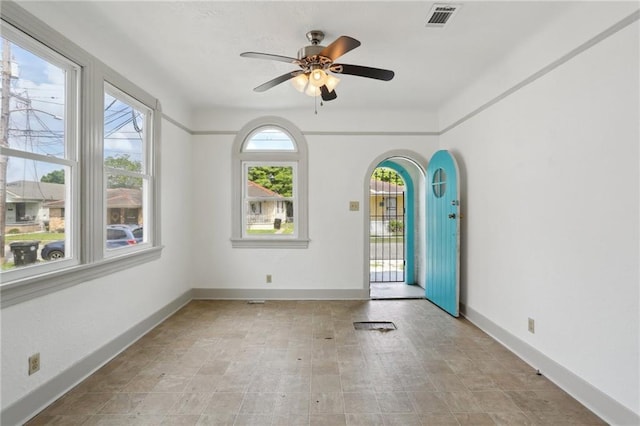 interior space with arched walkways, visible vents, a ceiling fan, and baseboards