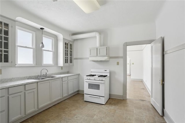 kitchen featuring glass insert cabinets, a sink, white range with gas stovetop, baseboards, and under cabinet range hood