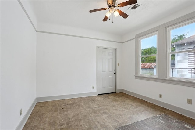 spare room featuring a healthy amount of sunlight, ceiling fan, visible vents, and baseboards