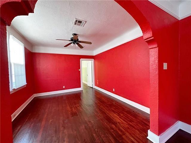 unfurnished room with wood finished floors, arched walkways, ceiling fan, baseboards, and a textured ceiling