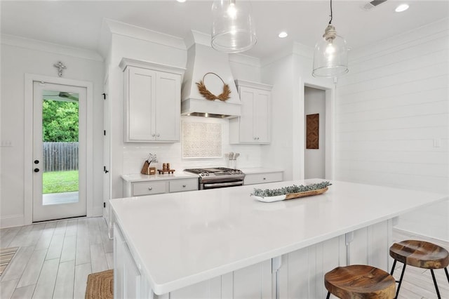 kitchen with stainless steel range with gas cooktop, decorative backsplash, crown molding, a kitchen island, and light countertops
