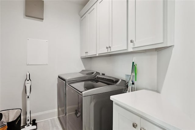 clothes washing area featuring baseboards, wood finished floors, cabinet space, and washing machine and clothes dryer