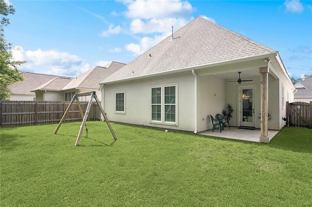 rear view of house with a playground, a patio area, ceiling fan, stucco siding, and a fenced backyard