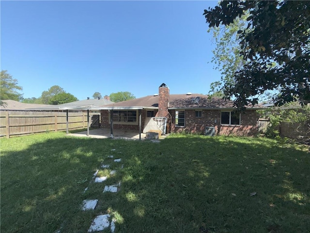 back of property featuring a chimney, a fenced backyard, a yard, and a patio area
