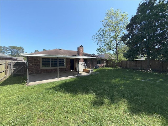rear view of property featuring a patio, a lawn, a fenced backyard, and a chimney