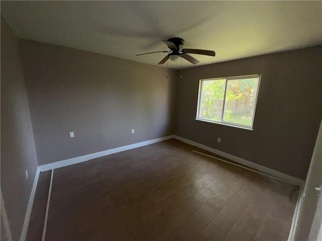 spare room with dark wood finished floors, ceiling fan, and baseboards