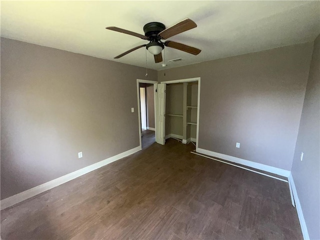 empty room featuring dark wood-type flooring, a ceiling fan, visible vents, and baseboards