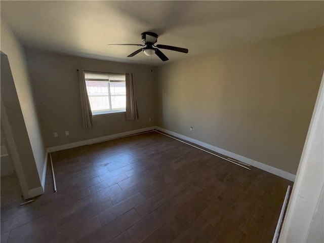 spare room featuring baseboards, ceiling fan, and dark wood-style flooring