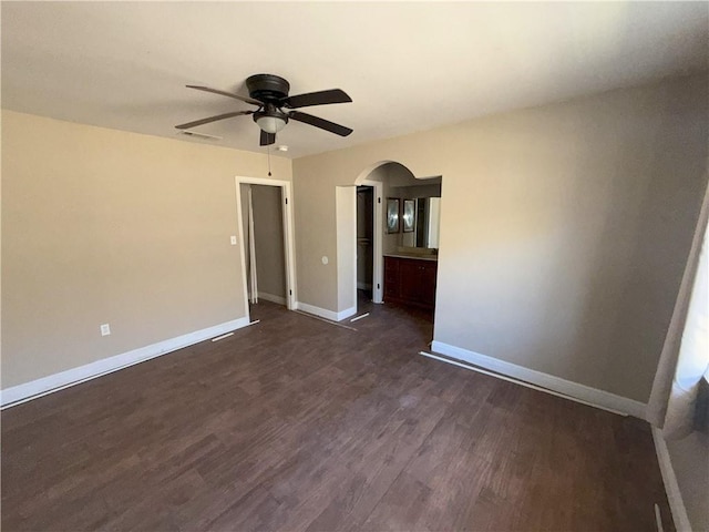 interior space featuring visible vents, ceiling fan, baseboards, arched walkways, and dark wood finished floors