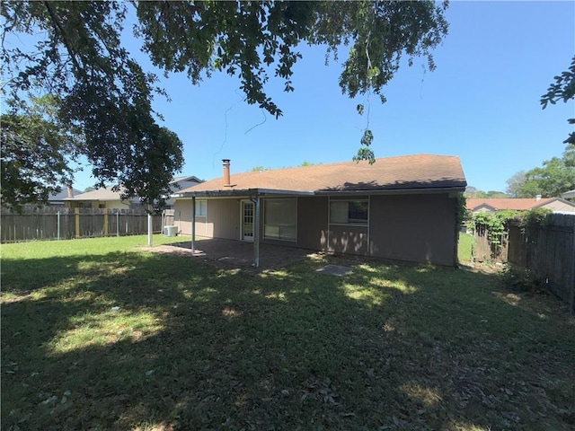 rear view of property with a lawn, central air condition unit, and a fenced backyard