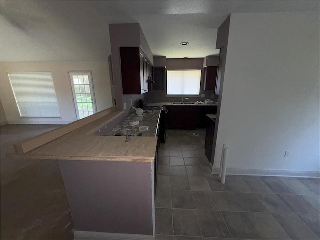 kitchen featuring black / electric stove, tile patterned floors, a peninsula, baseboards, and dark brown cabinets