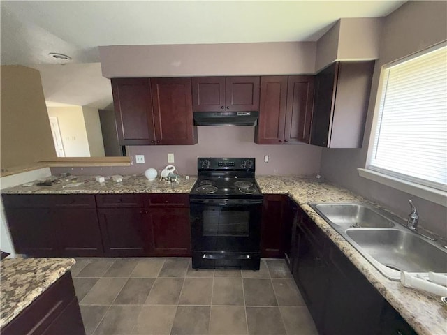 kitchen with a sink, under cabinet range hood, light tile patterned floors, light stone counters, and black range with electric cooktop