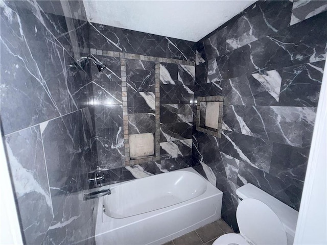 bathroom with tile walls, bathing tub / shower combination, and toilet