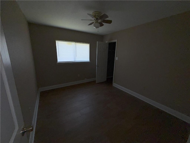 empty room with baseboards, wood finished floors, and ceiling fan