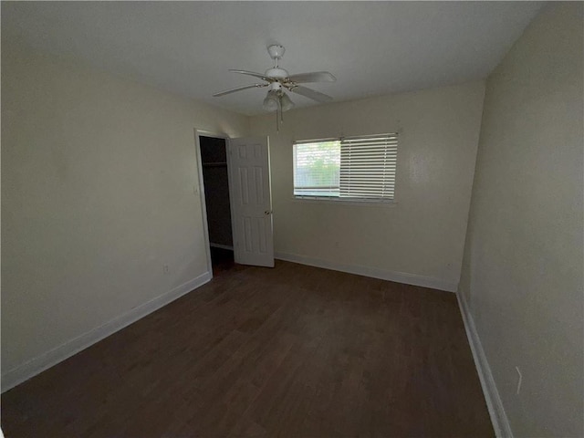 unfurnished room with dark wood-style flooring, a ceiling fan, and baseboards