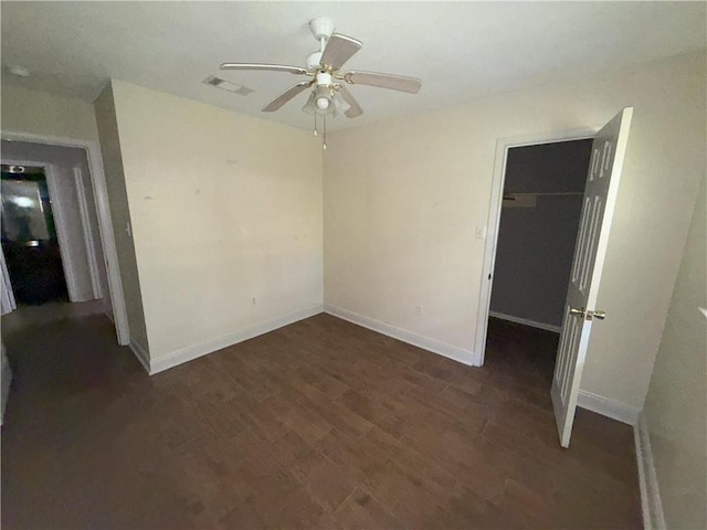 unfurnished bedroom with a spacious closet, wood finished floors, a closet, baseboards, and visible vents