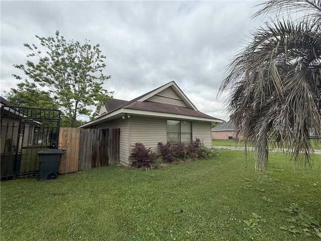 view of home's exterior with fence and a yard