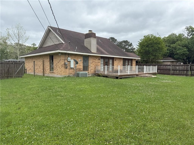 back of property featuring a lawn, a wooden deck, brick siding, and a fenced backyard