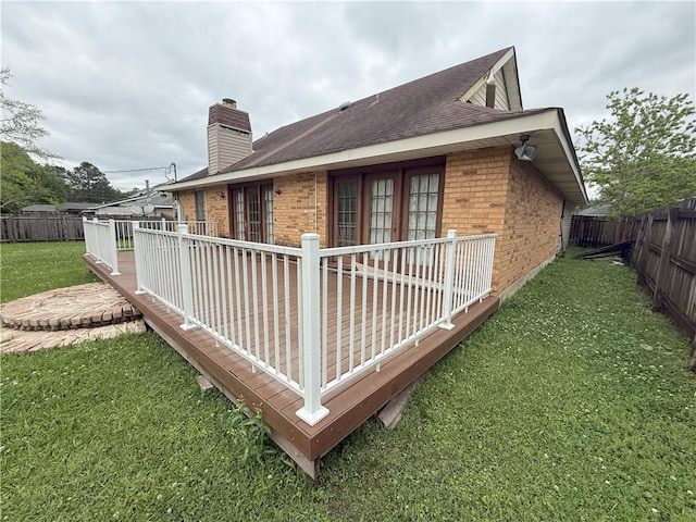 view of property exterior featuring brick siding, a fenced backyard, a lawn, a chimney, and a deck