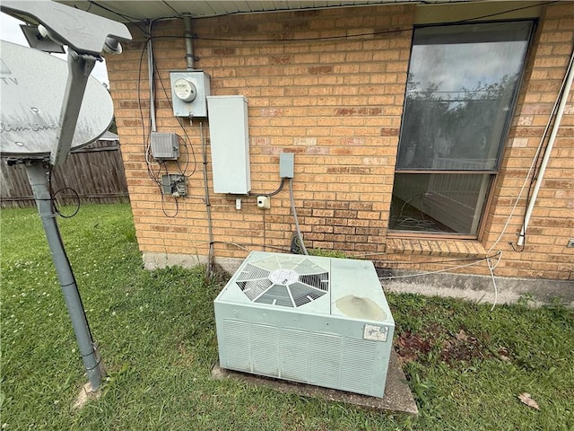 exterior details with cooling unit, fence, electric meter, and brick siding