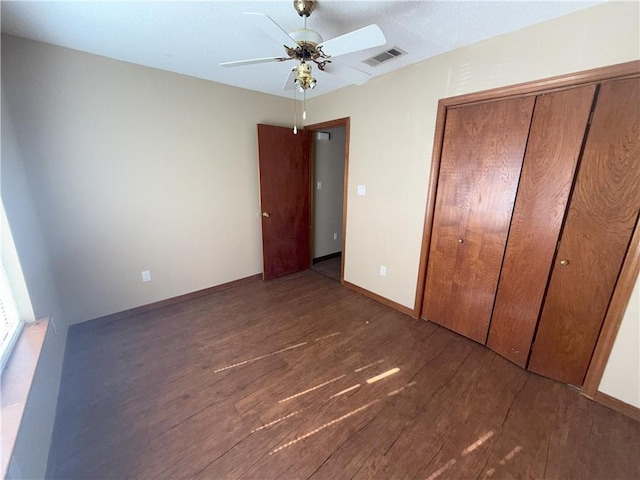 unfurnished bedroom with visible vents, ceiling fan, baseboards, a closet, and wood finished floors
