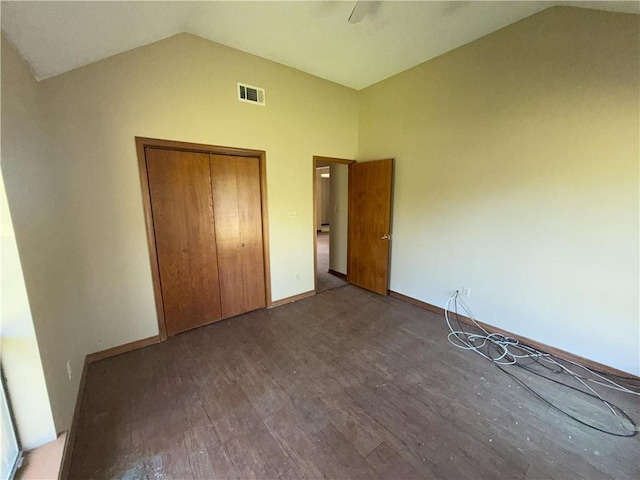 unfurnished bedroom with a closet, a ceiling fan, visible vents, vaulted ceiling, and wood finished floors
