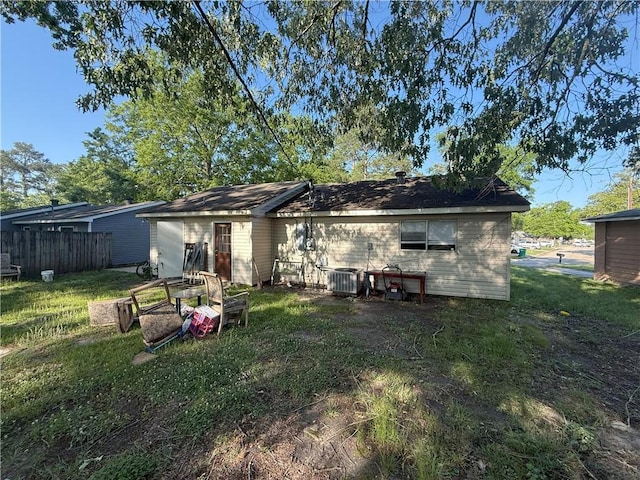 rear view of property featuring a lawn, fence, and central AC unit