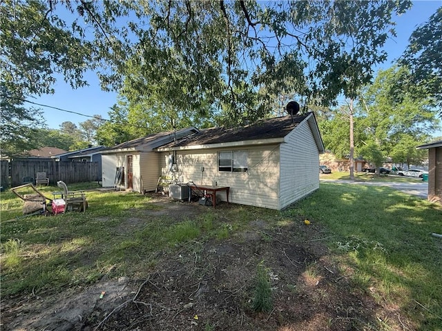 rear view of house featuring fence and a lawn