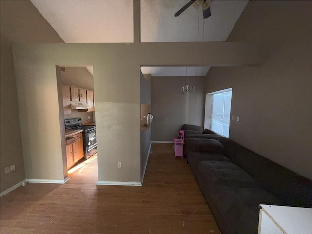 living room with ceiling fan with notable chandelier, baseboards, vaulted ceiling, and light wood-style floors