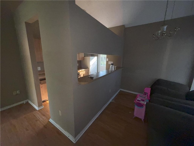 interior space featuring an inviting chandelier, wood finished floors, lofted ceiling, and baseboards