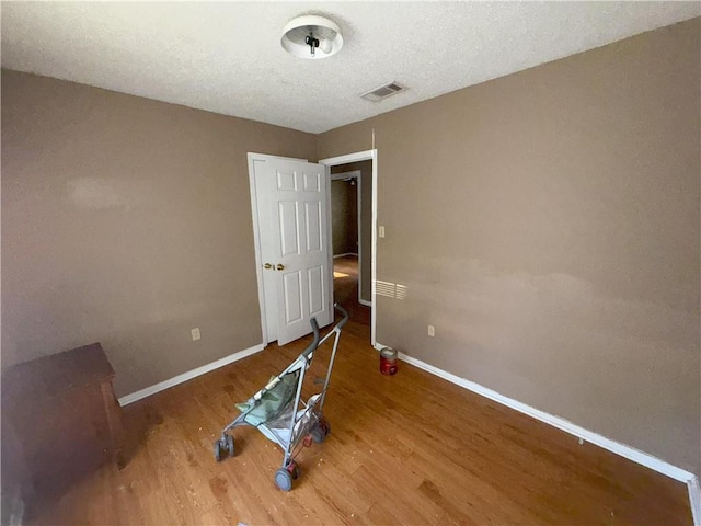 spare room with baseboards, visible vents, and wood finished floors