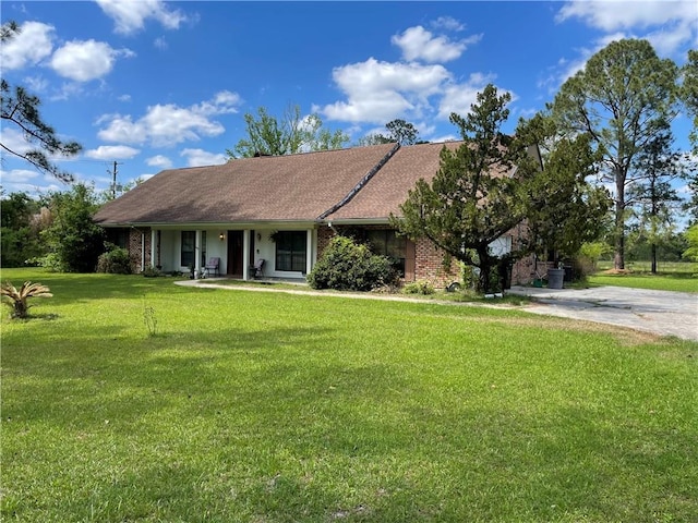 ranch-style house with covered porch, concrete driveway, brick siding, and a front lawn
