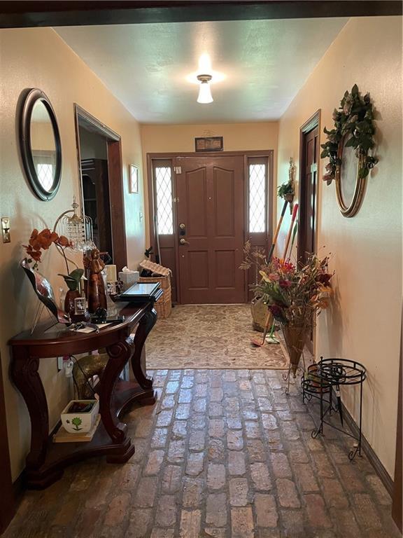 foyer entrance with baseboards and brick floor