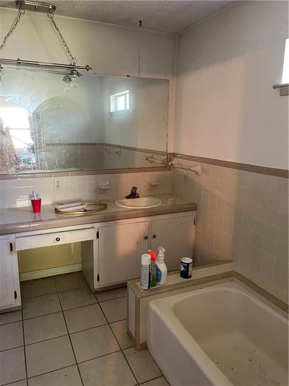 bathroom featuring a textured ceiling, a bath, tile walls, tile patterned floors, and vanity